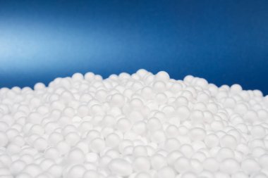 Beyaz polistiren köpük boncuk topu, kırılgan şeyler için yapay köpük makinesinden düşerek modern lüks arka planda, fotokopi alanı ve küresel ısınma koruması atığı olan mavi kutuya konur.