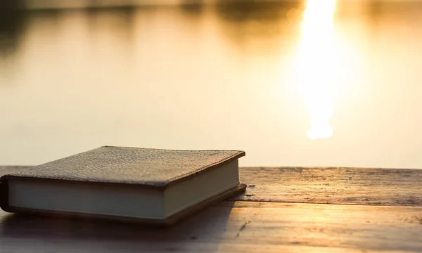 Notebook on the wooden Table with bokeh Sunset background of Lake, Relax Holiday Time in the Park, Happy Learning Concept