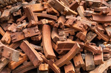 Eski terk edilmiş tren parçası üretim fabrikasında paslı çelik fren yastığı yığını. Eski demiryolu endüstrisi.