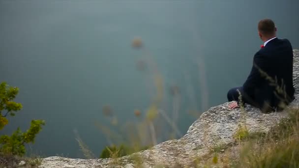 男は崖のスローモーションの端に座ってください。 — ストック動画