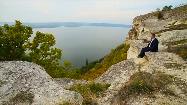 Egy ember ül a szélén a szikla-lassú mozgás — Stock videók