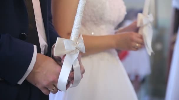 Жених и невеста держат в руках зажженные свечи — стоковое видео