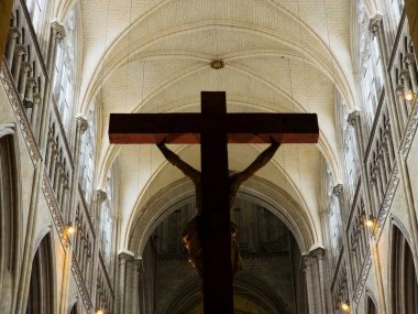 Ahşap bir haç silueti yükselen Gotik kubbeli tavana karşı duruyor ve Rouen Katedrali 'nin kavisli kemerleri yumuşak, ruhani ışıkla yıkanmış..