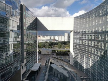 La Defense, Paris 'te Ronde Meydanı' nın yüksek manzarası. Mavi-gri cepheli ve cam yansımalı modern ofis binaları karmaşık bir çelik ve cam gölgelik altında otururlar..
