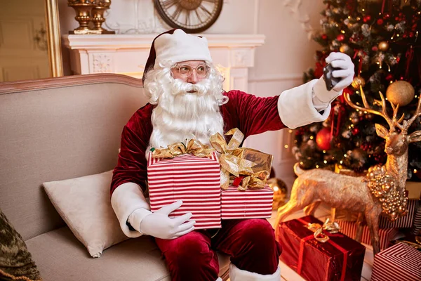 Santa Claus Sentado Sofá Hablando Por Teléfono Móvil Cerca Chimenea — Foto de Stock