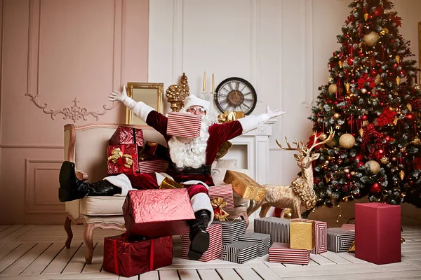 Santa Claus lay down to rest on the sofa with a bunch of gifts near the fireplace and christmas tree . New year and Merry Christmas , happy holidays concept