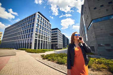 İş merkezi Wroclaw, Polonya 'daki modern mimari binaların arka planında konuşan güzel bir iş kadını.