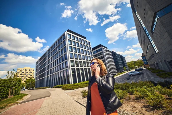 Beautiful businesswoman talking on the phone on the background of modern architecture buildings in the business center Wroclaw, Poland