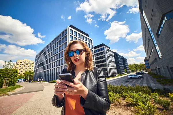 Beautiful businesswoman talking on the phone on the background of modern architecture buildings in the business center Wroclaw, Poland