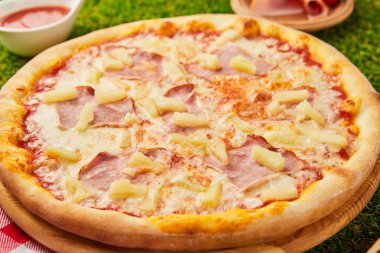 Geleneksel İtalyan pizzası, jambon, mozzarella ve yeşil çimenli ananas.