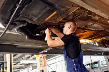 Yakışıklı oto tamircisi, benzin istasyonunda çalışan otomobili kontrol ediyor. Neşeli erkek işçi arabayla sorunu çözüyor. Sorun çözme kavramı