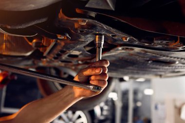 Yakışıklı oto tamircisi, benzin istasyonunda çalışan otomobili kontrol ediyor. Neşeli erkek işçi arabayla sorunu çözüyor. Sorun çözme kavramı