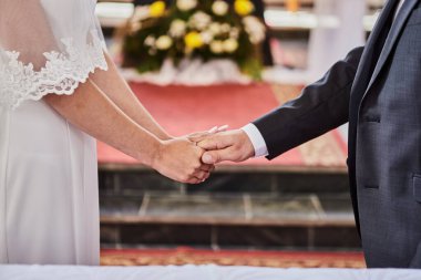 Yeni evliler Katolik kilisesinde bir düğün sırasında el ele tutuşuyorlar.