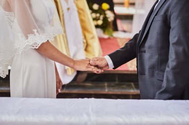 Yeni evliler Katolik kilisesinde bir düğün sırasında el ele tutuşuyorlar.