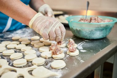 Şefin elleri masa üzerine un serpiştirilmiş el yapımı ravioli ve khinkali ile kesilmiş tahtaların arka planına hamur tatlısı heykeli yapıyor. Lezzetli ev yemekleri..