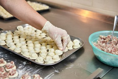 Şefin elleri masa üzerine un serpiştirilmiş el yapımı ravioli ve khinkali ile kesilmiş tahtaların arka planına hamur tatlısı heykeli yapıyor. Lezzetli ev yemekleri..