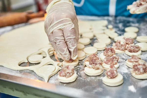 Şefin elleri masa üzerine un serpiştirilmiş el yapımı ravioli ve khinkali ile kesilmiş tahtaların arka planına hamur tatlısı heykeli yapıyor. Lezzetli ev yemekleri..