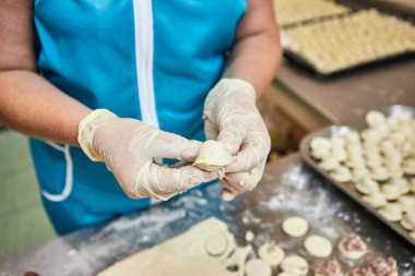 Şefin elleri masa üzerine un serpiştirilmiş el yapımı ravioli ve khinkali ile kesilmiş tahtaların arka planına hamur tatlısı heykeli yapıyor. Lezzetli ev yemekleri..