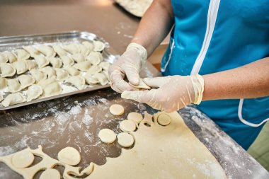 Kadının elleri arka planda el yapımı mantı, ravioli ve masaya un serpiştirilmiş khinkali köfteleri yontuyor. Lezzetli ev yemekleri..