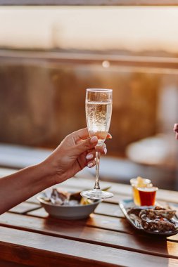 Yaz günbatımında taze istiridye yiyip soğuk Prosecco şarabı içen bir kadın. Deniz ürünleri lezzetleri.