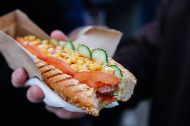 Dışarıdaki kağıt tepside sebzeli, mısırlı ve soslu sosisli sandviçe yakın çekim. Yüksek kalite fotoğraf