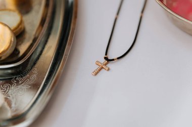 Vaftiz töreni sırasında gümüş tepside duran siyah kordondaki altın haç kolye. Yüksek kalite fotoğraf