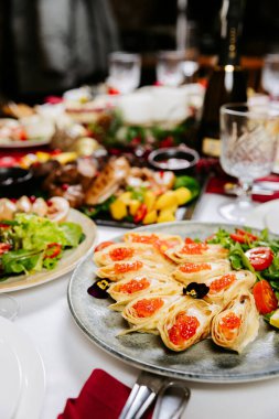 Şenlikli krep ruloları, kırmızı havyar, yeşiller ve zarif masa düzeninde vişneli domatesler. Yüksek kalite fotoğraf