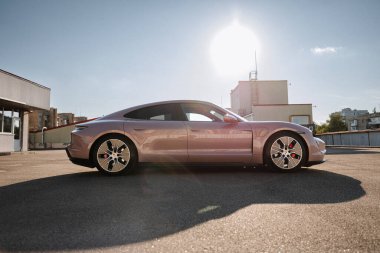 Vinnitsya, Ukrayna - 15 Temmuz 2025: Çatıdaki parlak güneşe karşı pembe Porsche Taycan profili. Yüksek kalite fotoğraf