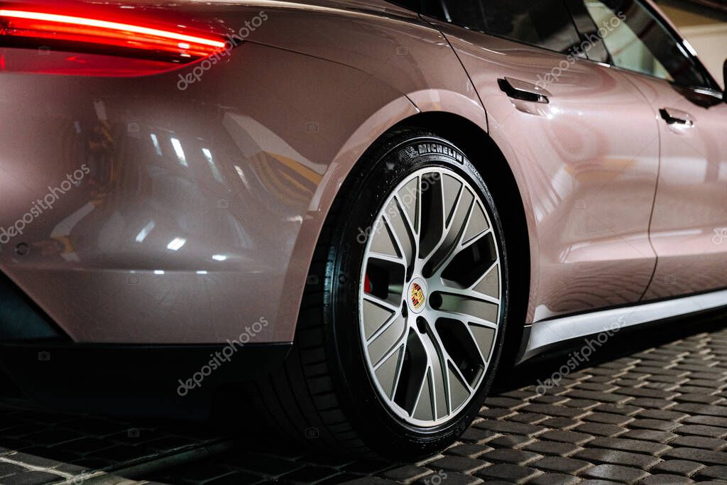 Vinnitsya, Ukraine - 15 July 2025:Rear wheel of pink Porsche Taycan in parking, LED taillight glowing. High quality photo
