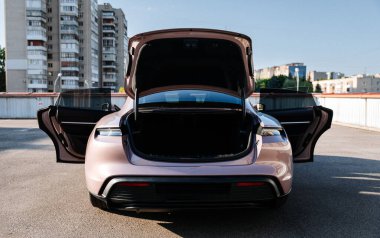 Vinnitsya, Ukrayna-15 Temmuz 2025: Pembe Porsche Taycan 'ın arkası, açık bagajlı ve park kapılı. Yüksek kalite fotoğraf