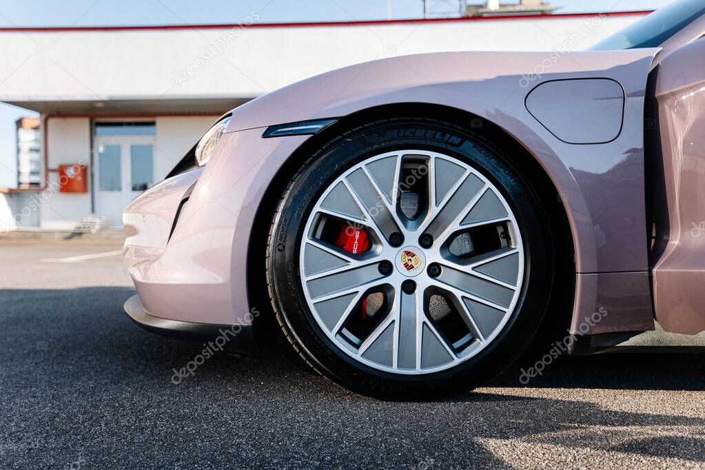 Vinnitsya,Ukraine - 15 July 2025: Front wheel of pink Porsche Taycan with logo and red brake caliper. High quality photo