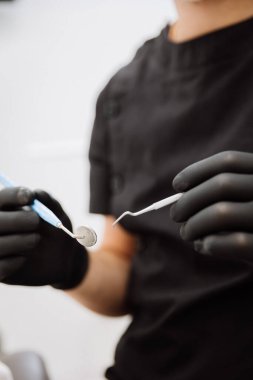 Siyah eldivenlerde ayna ve pulluk tutan dişçi klinik diş muayenesi. Yüksek kalite fotoğraf