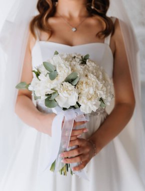 Gelinin elinde parlak minimalist düğününde kurdeleli beyaz bir buket var. Yüksek kalite fotoğraf