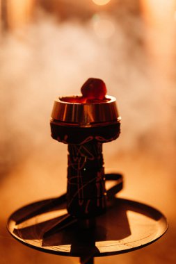 Parlayan kömürlü nargile kasesi ve sıcak Bokeh bar ışığında sürüklenen duman. Yüksek kalite fotoğraf