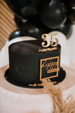 Siyah doğum günü pastası. Altın rengi 35 'lik pasta. Şık bir partide pampa dekoru olan kaidede. Yüksek kalite fotoğraf