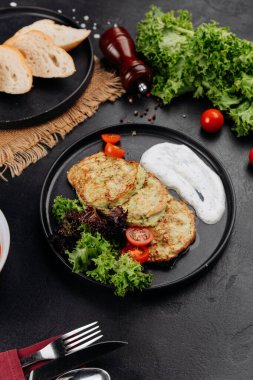Yoğurt soslu kabaklı börek ve siyah tabakta salata, restoran servisi. Yüksek kalite fotoğraf