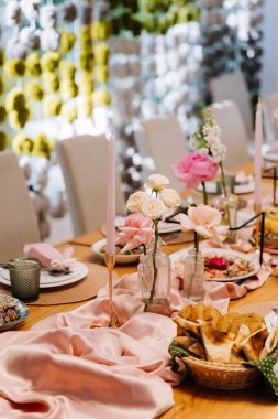 Şenlikli bir akşam yemeği için pembe mumlar ve güllerle süslü zarif bir masa, yumuşak pastel dekoru. Yüksek kalite fotoğraf