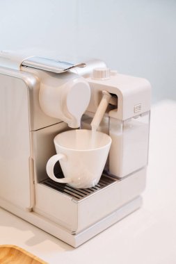 Modern ofis mutfağında, espresso makinesinden çıkan süt köpüğü fincana buharlaşıyor. Yüksek kalite fotoğraf