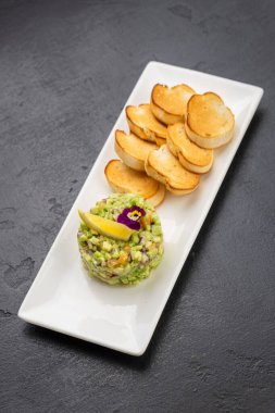 Beyaz tabakta kızarmış baget dilimli avokado tartare, gurme aperatifi. Yüksek kalite fotoğraf