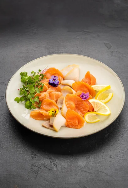 Limonlu, mikroyeşillikli ve tabakta yenilebilir çiçekli somon sashimi. Yüksek kalite fotoğraf