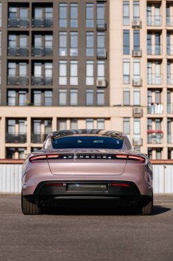 Vinnitsya, Ukrayna - 15 Temmuz 2025: Pembe Porsche Taycan elektrikli sedan 'ın bina tarafından park edilmiş arka manzarası. Yüksek kalite fotoğraf