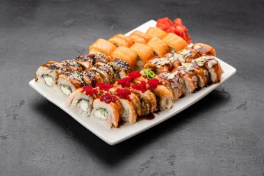 Somon balıklı suşi ruloları, beyaz tabakta susam ve jöle, restoran servisi. Yüksek kalite fotoğraf