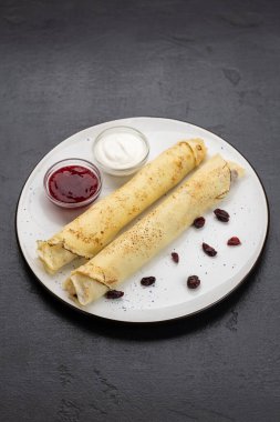 Beyaz tabakta reçelli krep ve ekşi krema, koyu arka planda üst manzara. Yüksek kalite fotoğraf