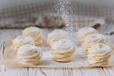 Vanilya zephyr 'in üzerine pudra şekeri dökülüyor parşömen üzerinde, kırsal arka planda. Yüksek kalite fotoğraf