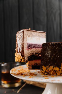 Katmanlı çikolatalı kremalı pasta dilimi, üzerinde ahududu reçeli, koyu arkaplan. Yüksek kalite fotoğraf