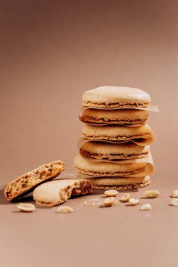 Kahverengi arka plan fotokopi alanının üzerinde kırıntıları ve fıstıkları olan bej makaronlar yığılmış. Yüksek kalite fotoğraf