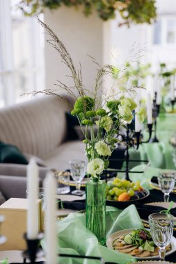 Zarif akşam yemeği partisi için mum ve cam süslemeli yeşil çiçek masası. Yüksek kalite fotoğraf