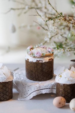 Paskalya pastaları ve yumurtalar dantel masanın üzerinde bahar çiçekleri dalları, yumuşak gün ışığı. Yüksek kalite fotoğraf