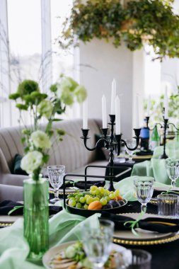 Şatafatlı yeşil ve siyah yemek masası. Mumlar, çiçekler ve cam eşyalar. Yüksek kalite fotoğraf