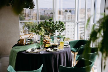 Şehir manzaralı, yeşillikli ve limonatalı güneşli bir kahvaltı masası. Yüksek kalite fotoğraf